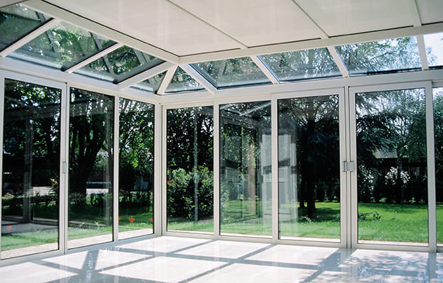 véranda en aluminium blanche avec vue sur jardin verdoyant